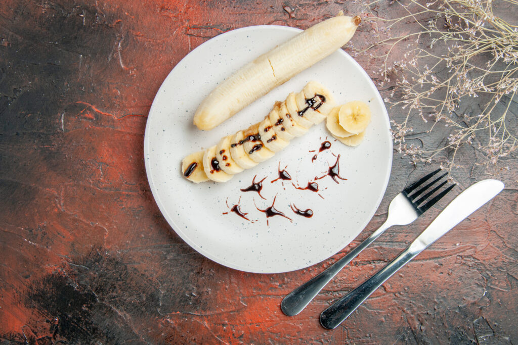 Fotografia przedstawia banany wraz z bidonem sportowym i ręcznikiem na tle siłowni. Scena podkreśla znaczenie tych owoców w regeneracji i utrzymaniu energii w diecie pudełkowej TIM Catering. Zachęca do aktywnego stylu życia.